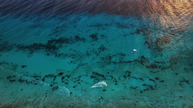 Aerial view of the turquoise water with kite surfers gliding across the waves, creating a striking contrast against the coral reefs, Bonaire, Caribbean Netherlands.