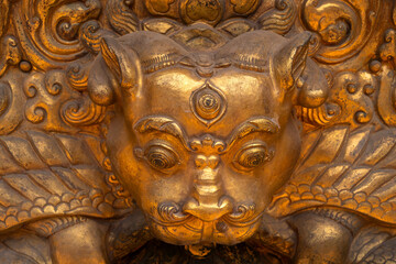 Close-up view of a wrathful Tibetan Buddhist deity in gold ornamental statue, symbolizing protection and the destruction of evil spirits.