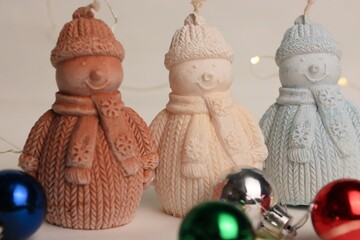 Snowman-Shaped Candles in Knitted Outfits with Christmas Balls and Garland — Cozy Holiday Decor for Winter Greetings, Advertising, and Interior Styling
