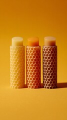 Three natural lip balms in vibrant honeycomb packaging arranged against a bright yellow background