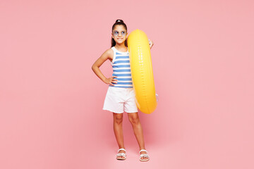 Traveler smiling happy kid child wearing blue casual clothes rest near hotel pool hold inflatable rubber yellow ring look aside isolated on plain pink background. Summer vacation sea sun tan concept.