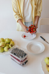 Caucasian woman preparing homemade fruit leather, slicing fresh fruit in her kitchen for a healthy snack. Part of a series on organic treats and natural living
