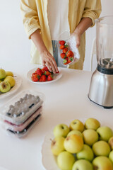 Caucasian woman preparing homemade fruit leather, slicing fresh fruit in her kitchen for a healthy snack. Part of a series on organic treats and natural living