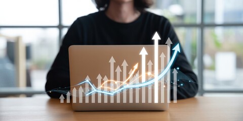 Business Growth - A person at a laptop with a digital overlay of a bar chart and a rising arrow, symbolizing business success and financial development