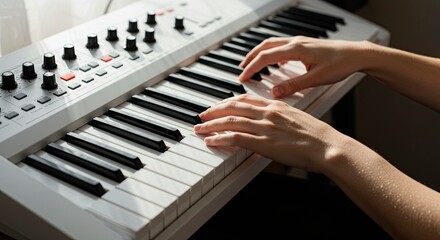 Fototapeta premium A person playing a white keyboard with black and white keys and knobs in a sunlit room