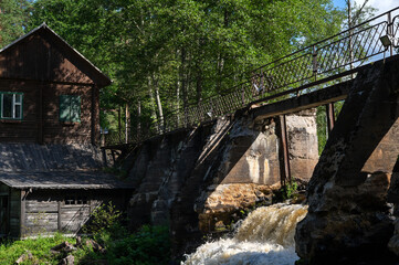 Old finnish hydroelectric dam on river with wooden house in summer