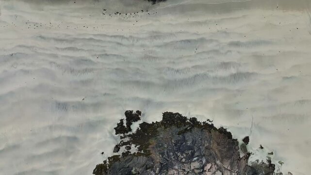 Birdseye aerial rising from sandy Rorvik beach to reveal sea, rocks, road, and scenic surroundings in Lofoten Norway