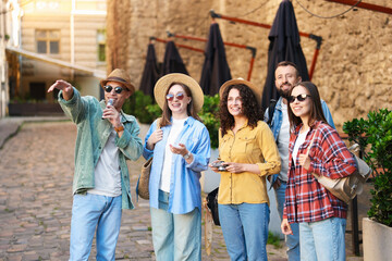 Guide with microphone and group of tourists on city street during excursion