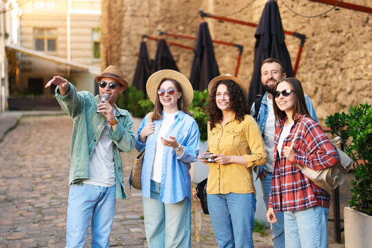 Guide with microphone and group of tourists on city street during excursion