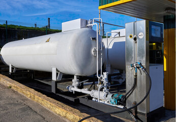 Metal LPG storage tank with piping, safety valves and fuel dispenser unit for vehicle refueling. Industrial liquefied petroleum gas storage, transport and distribution for automotive and energy sector