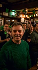 Obraz premium A happy middle-aged man in a green sweater smiles at a camera during a lively St. Patrick's Day celebration with friends in a traditional Irish pub.