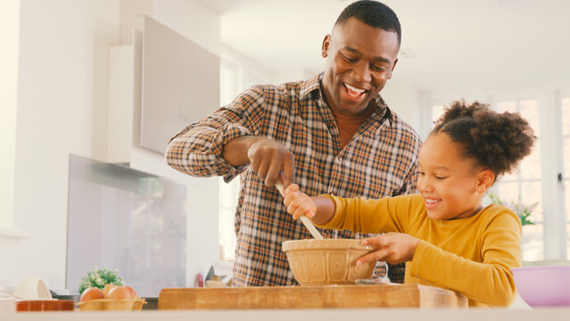 Family Shot With Father And Daughter Baking At Home In Kitchen Mixing Ingredients In Bowl
