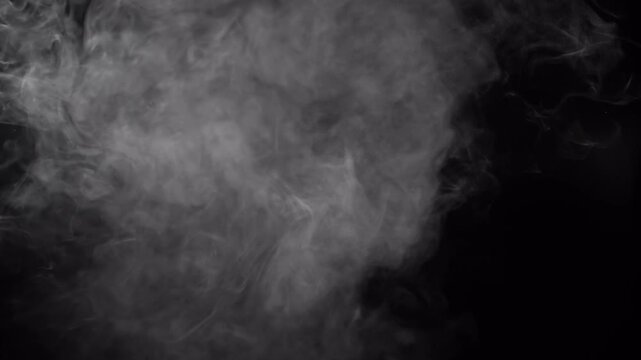 Dense vape smoke cloud being exhaled and expanding in the air over a dark backdrop.