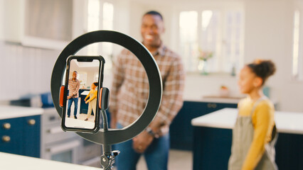 Father And Daughter At Home Recording Video Of Dance Routine For Social Media On Mobile Phone