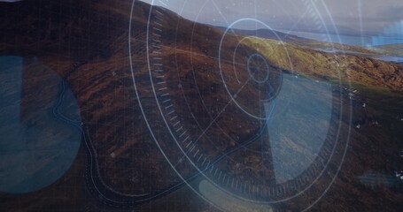 Rugged hillside descending coastal bay, showing winding road and HUD overlay with circles and lines