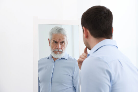 Man seeing himself as elder in mirror. Conceptual collage about past and future, flow of time, age