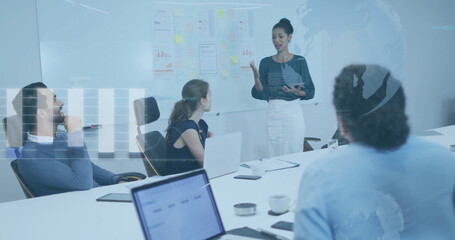 Presenting Asian woman explaining charts on whiteboard in conference room, with tablet and laptops