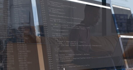 Developer wearing shirt and glasses typing code in office, with 3 screens showing JavaScript code