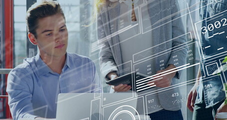 Collaborating professionals reviewing digital data overlays in office workspace, laptop and tablet