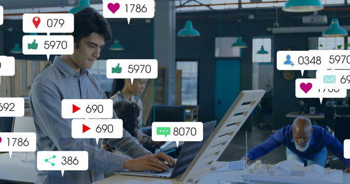 Typing Native American man working at coworking space with scale model and social icons, copy space