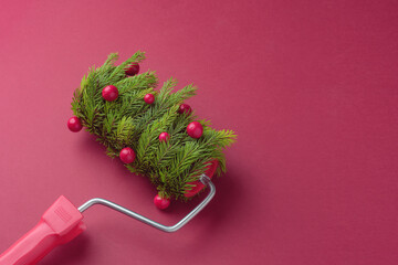 Paint roller styled as festive fir with red berries on red background sets joyful DIY vibe for...