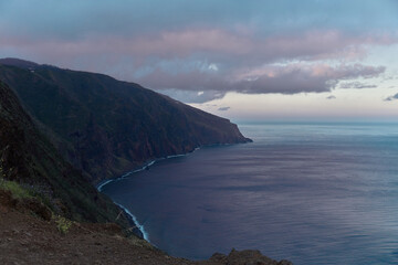 Expansive View of Rugged Coastal Cliffs and Serene Ocean at Twilight Under a Clouded Sky