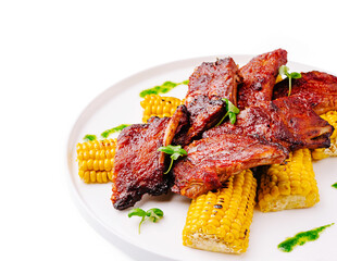 Grilled ribs served with corn on a white plate at a summer barbecue