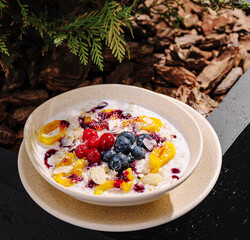 Fresh fruit bowl topped with berries and yogurt served outdoors