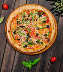 Delicious pizza topped with fresh vegetables and meat on wooden table