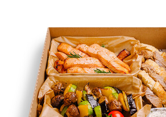 Healthy grilled salmon with vegetables in a takeout box from a local restaurant