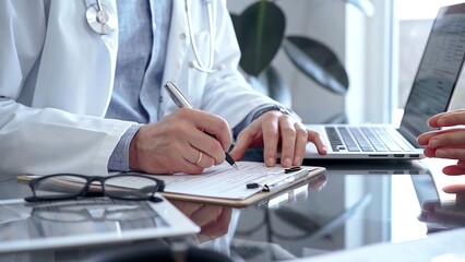Doctor man is writing something while consulting patient on the glass desk and a clipboard in medical office. Medicine concept