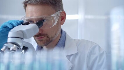 Man scientist with protective glasses and gloves is using micros