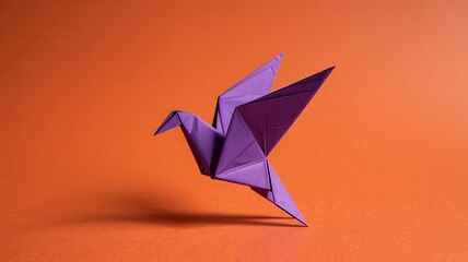 A single vibrant purple origami paper crane artfully folded and casting a subtle shadow against a warm solid orange background