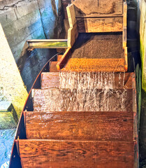 Wooden water wheel at at a old flour mill driving wheat grindng stones