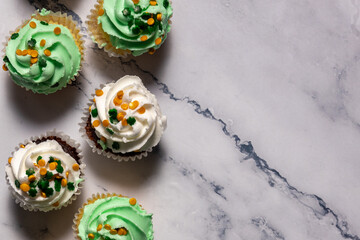 Green-frosted cupcakes topped with orange sprinkles