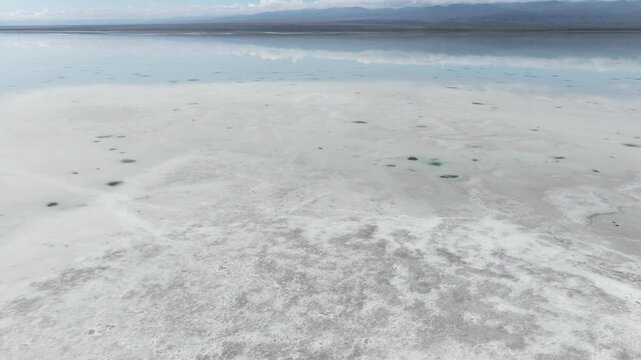 Aerial view of the Chaka Lake salt flats reveals a textured landscape where the sky mirrors the ground in a serene, pale blue, Chaka Lake, Qinghai, China.