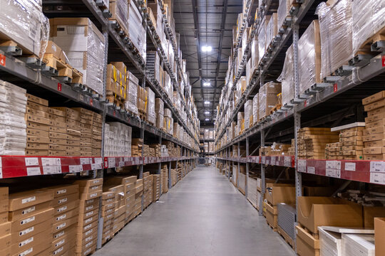 Rows of stacked cardboard boxes in a long narrow warehouse