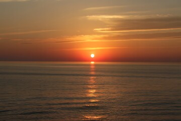 Obraz premium Vibrant sunset over the ocean with golden light reflecting on the water at dusk