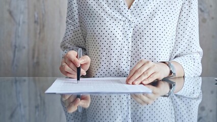 Businesswoman analyzing document at desk. Close-up of a professional auditor or lawyer reviewing a lengthy paper report in office setting. Business people concept