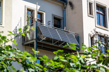 A balcony power plant with solar panels mounted on a residential building's railing. This image...