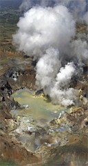 Aerial view of a volcanic crater with steaming pool