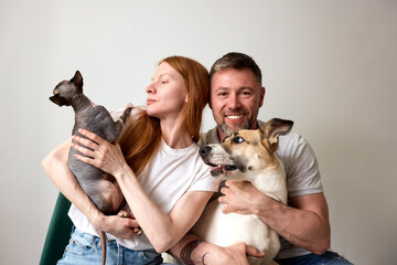 Couple Smiling with Sphynx Cat and Mixed Breed Dog at Home