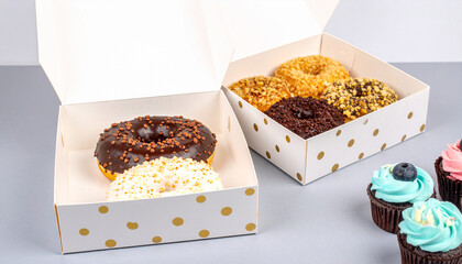 Donut Delight: An assortment of colorful donuts and cupcakes sit in decorative boxes, tempting the viewer with their sweet, delightful presence, in a vivid and high-angle shot.