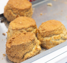 Delicious golden scones cooling on metal tray, freshly baked and ready to be enjoyed with clotted cream and jam