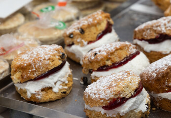 Freshly baked welsh cakes filled with jam and clotted cream, dusted with powdered sugar, displayed on a market stall in Cardiff, Wales