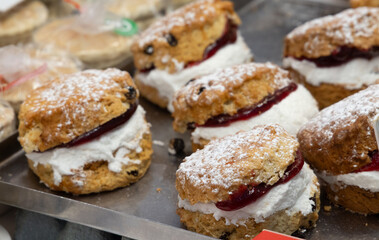 Freshly baked scones filled with jam and cream, dusted with powdered sugar, on display at a market stall in Cardiff, Wales