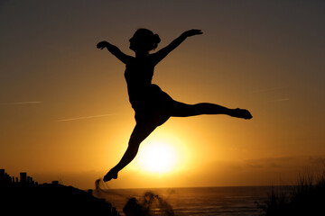 Beautiful girl dancing at sunset on the beach