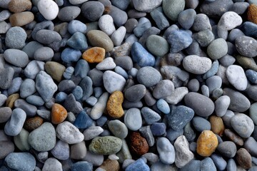 An overhead shot of smoothed multicolored pebbles of various sizes filling the frame