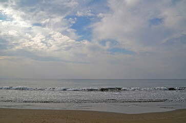 Calm Sea with Cloudy Sky. A calm sea with gentle waves rolling onto a sandy beach under a beautiful cloudy sky. The horizon line is visible, creating a peaceful and serene landscape, Cyprus