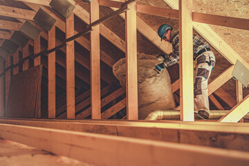 Obraz premium Caucasian Worker Installing Insulation in Attic During Home Renovation Project